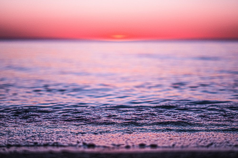 the sun is setting over the water at the beach