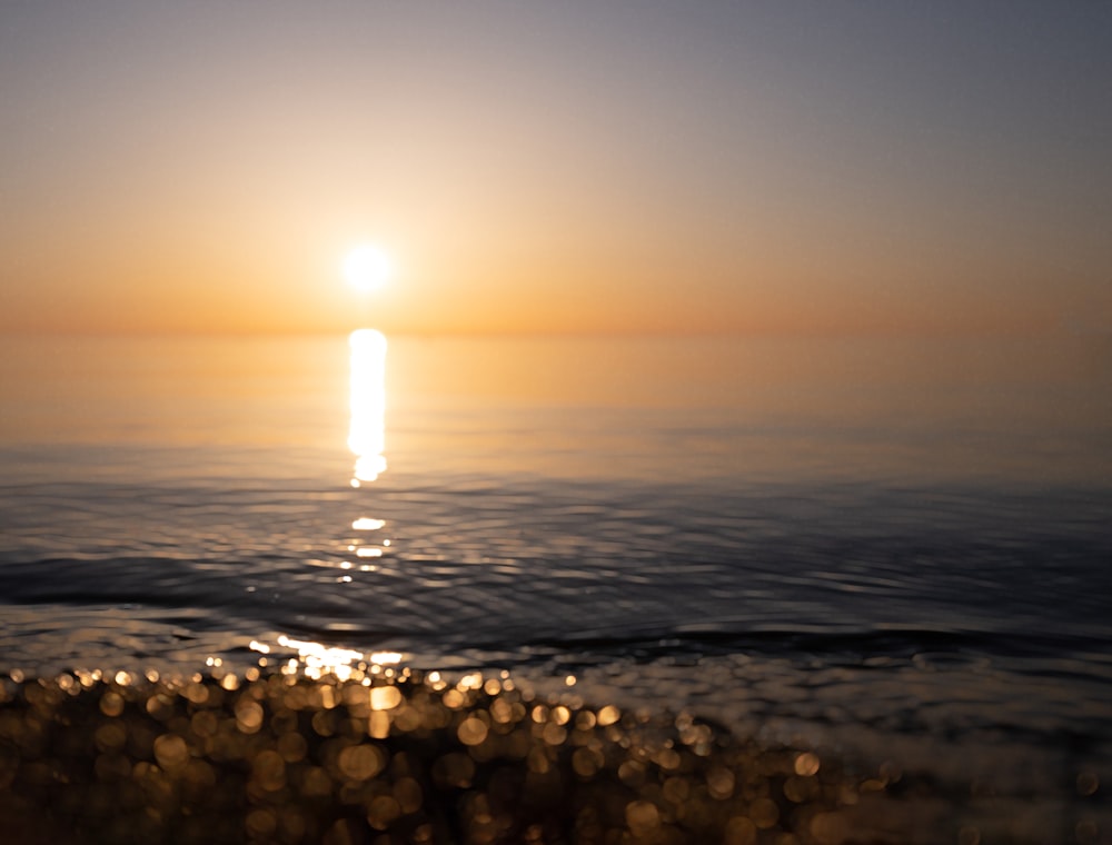 the sun is setting over the water at the beach