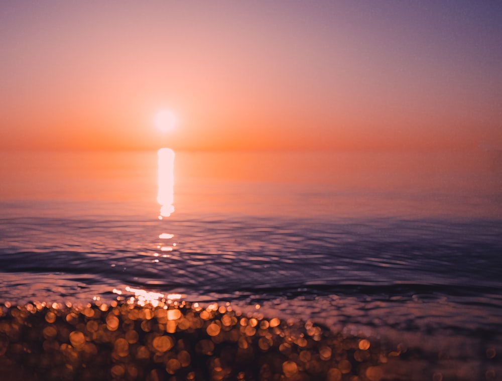 the sun is setting over the water at the beach