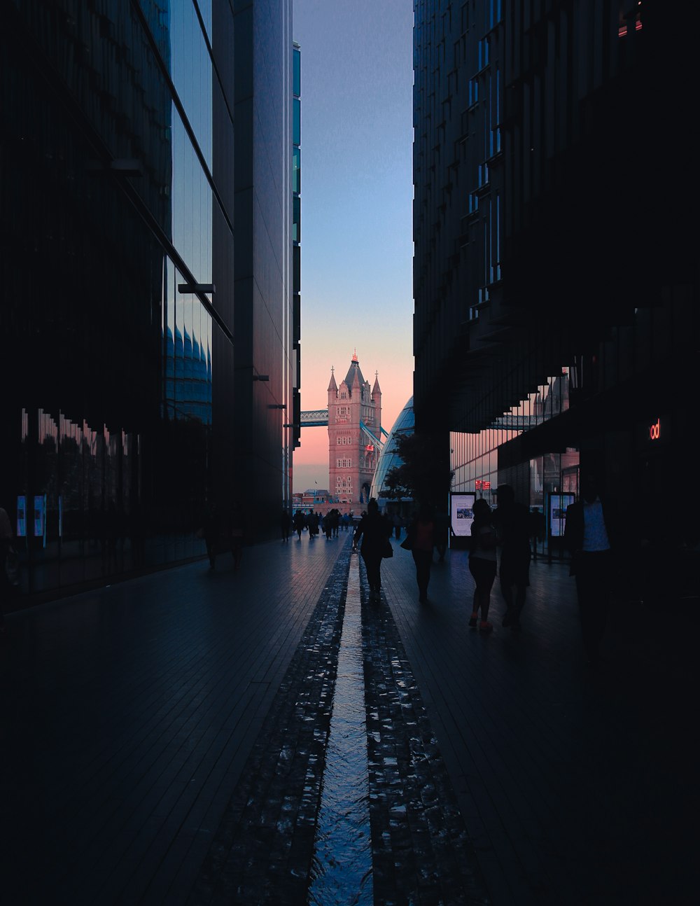 a group of people walking down a street next to tall buildings