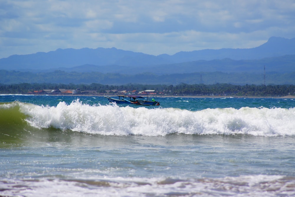 a boat in the ocean with mountains in the background