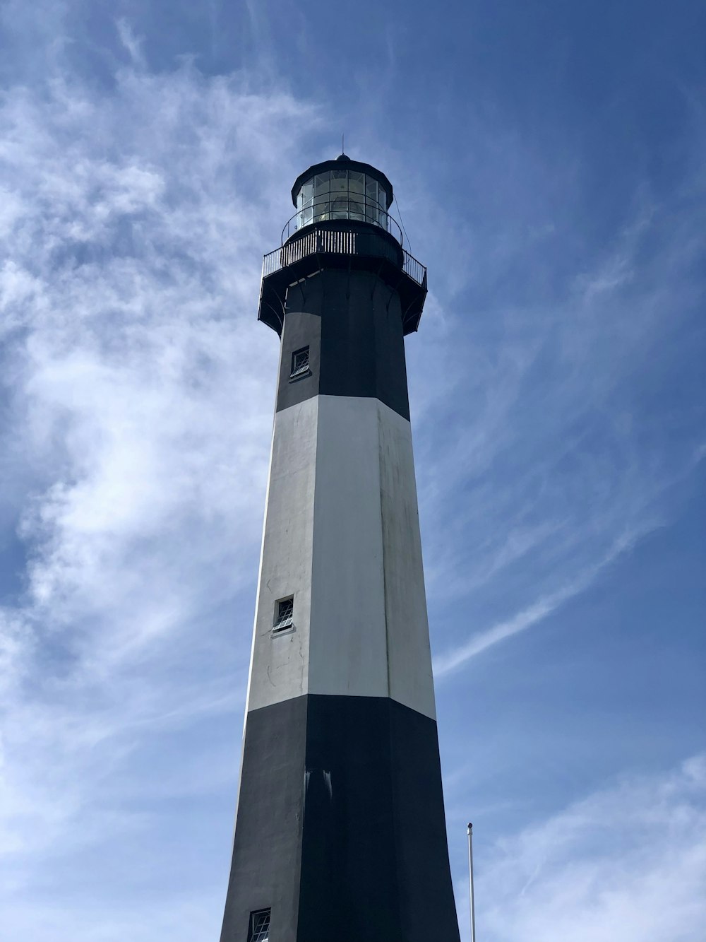 a black and white lighthouse under a blue sky