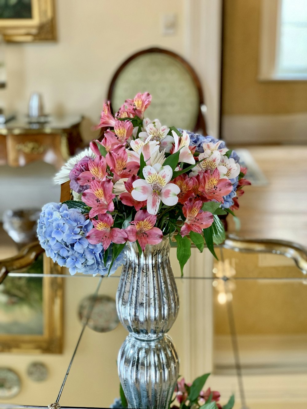 a silver vase filled with colorful flowers on top of a table