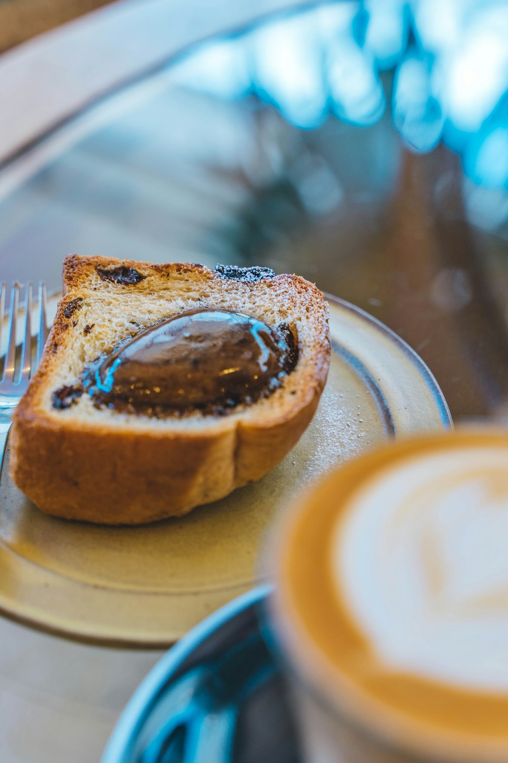 a piece of bread on a plate next to a cup of coffee