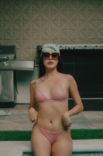 a woman in a bikini standing next to a pool
