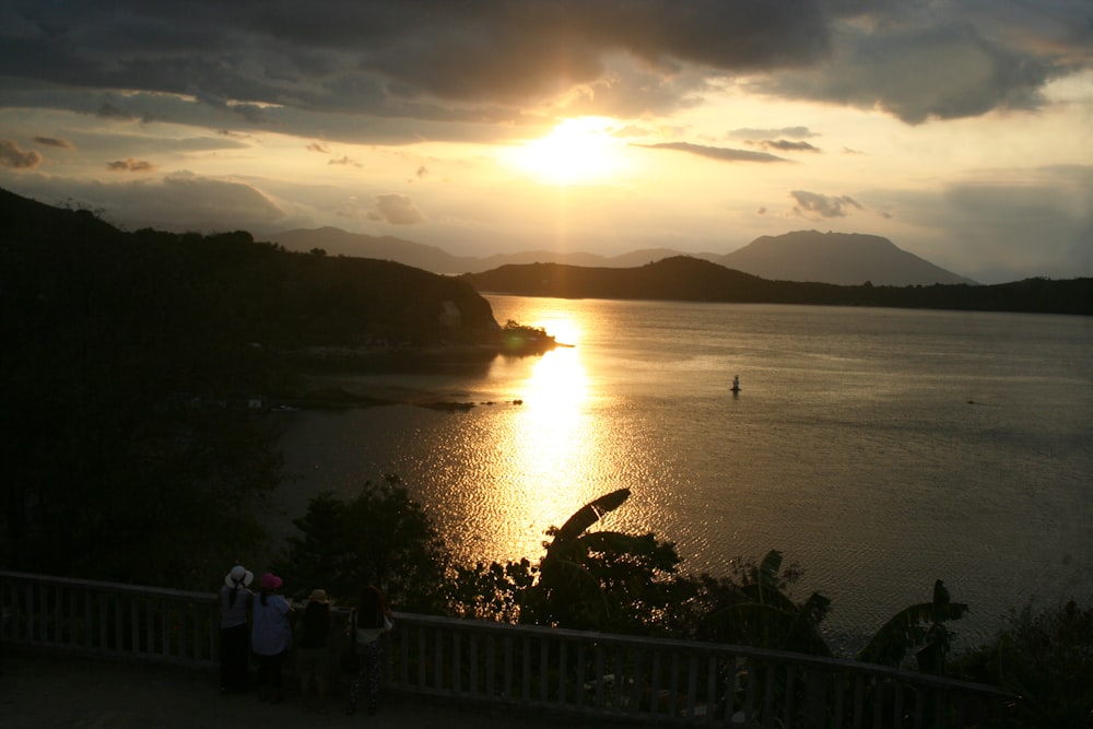 a group of people standing on top of a hill next to a body of water