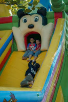 Bright inflatable slide with kids playing and laughing on a clear day