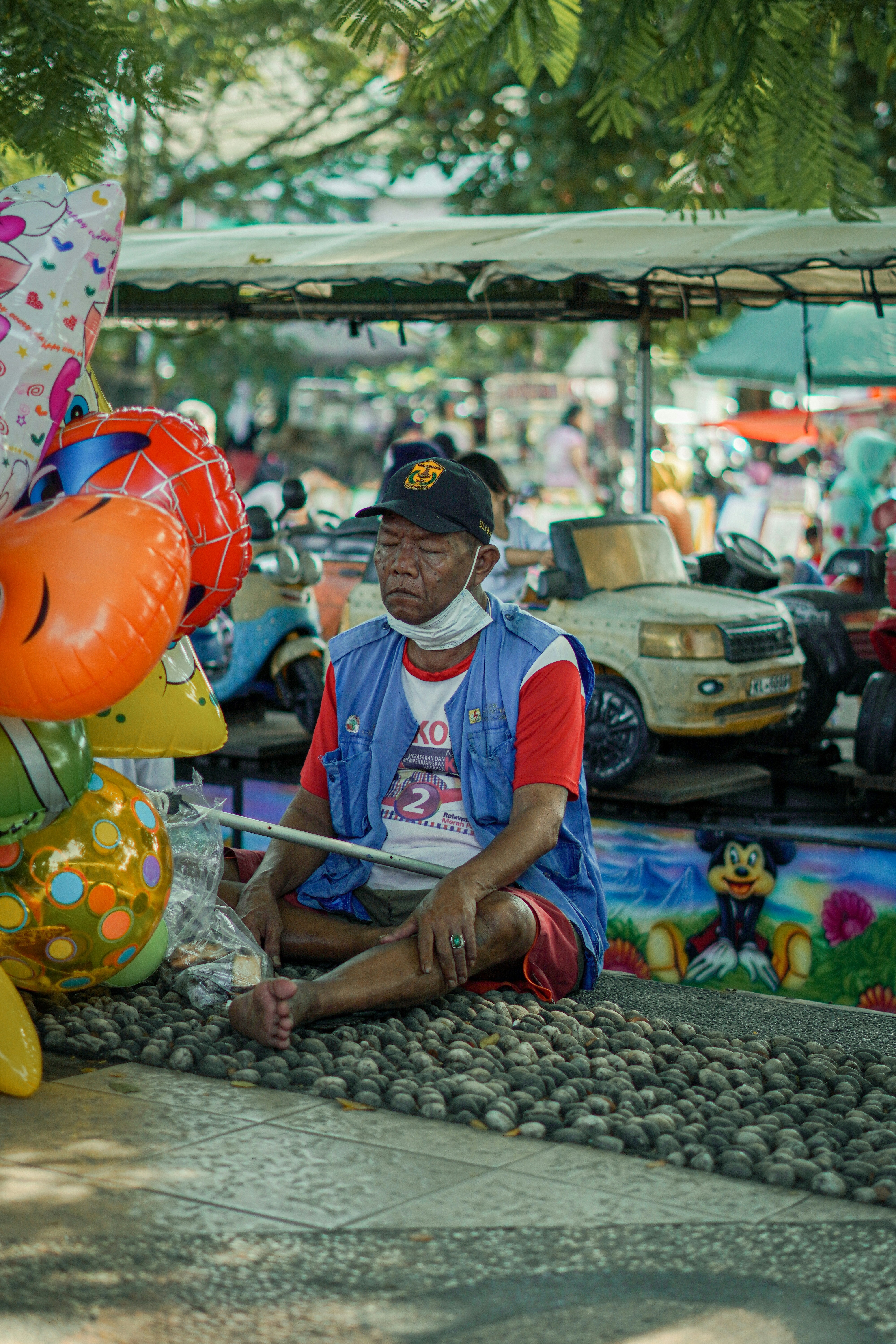 a man sitting on the ground next to a bunch of balloons