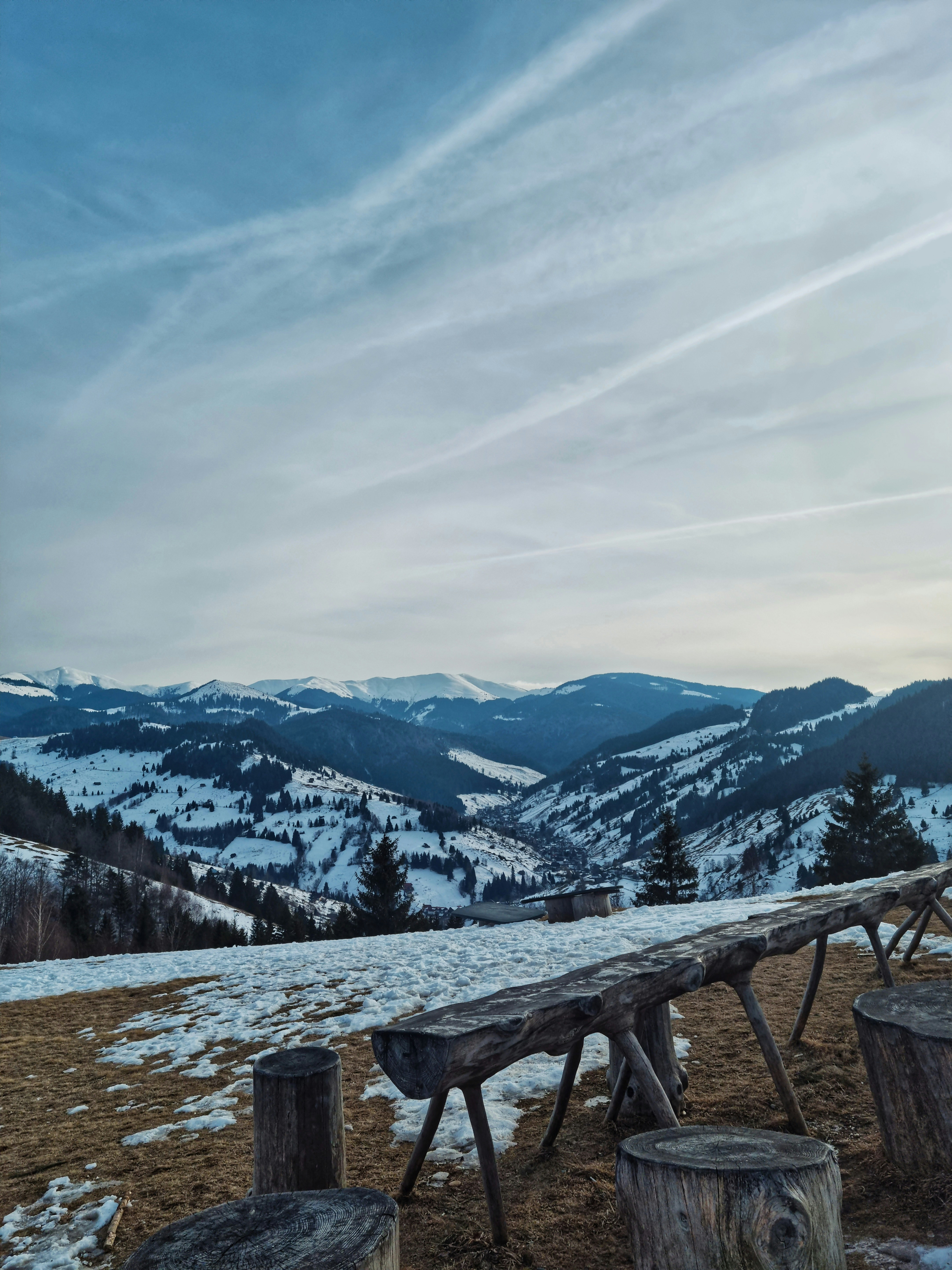 a wooden bench sitting on top of a snow covered hillside