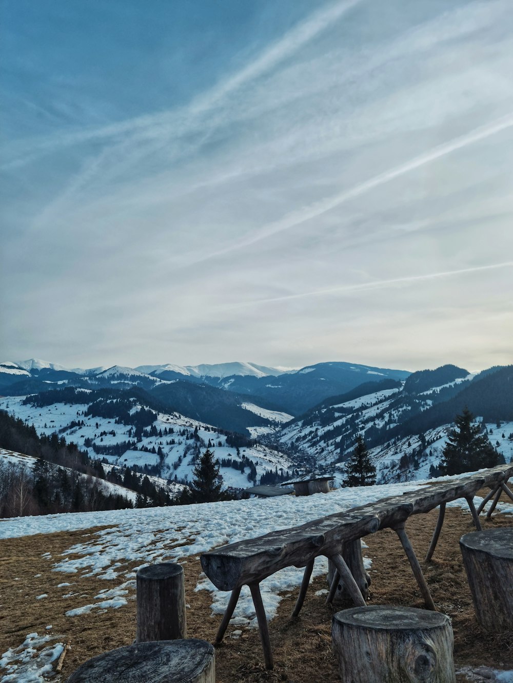 a wooden bench sitting on top of a snow covered hillside