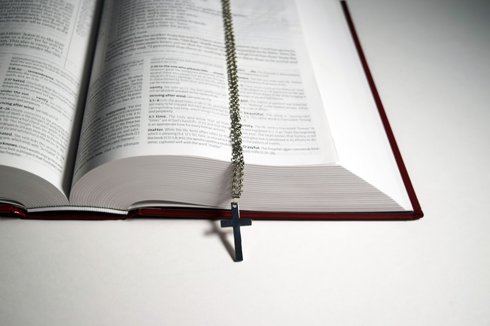 an open book with a cross hanging from it