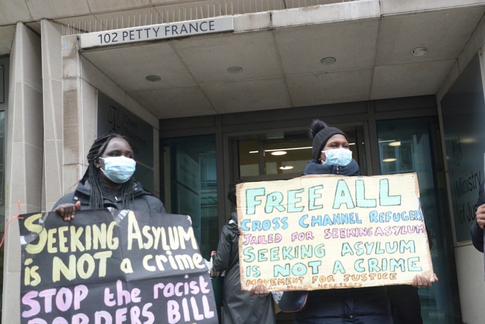 a group of people standing outside of a building holding signs