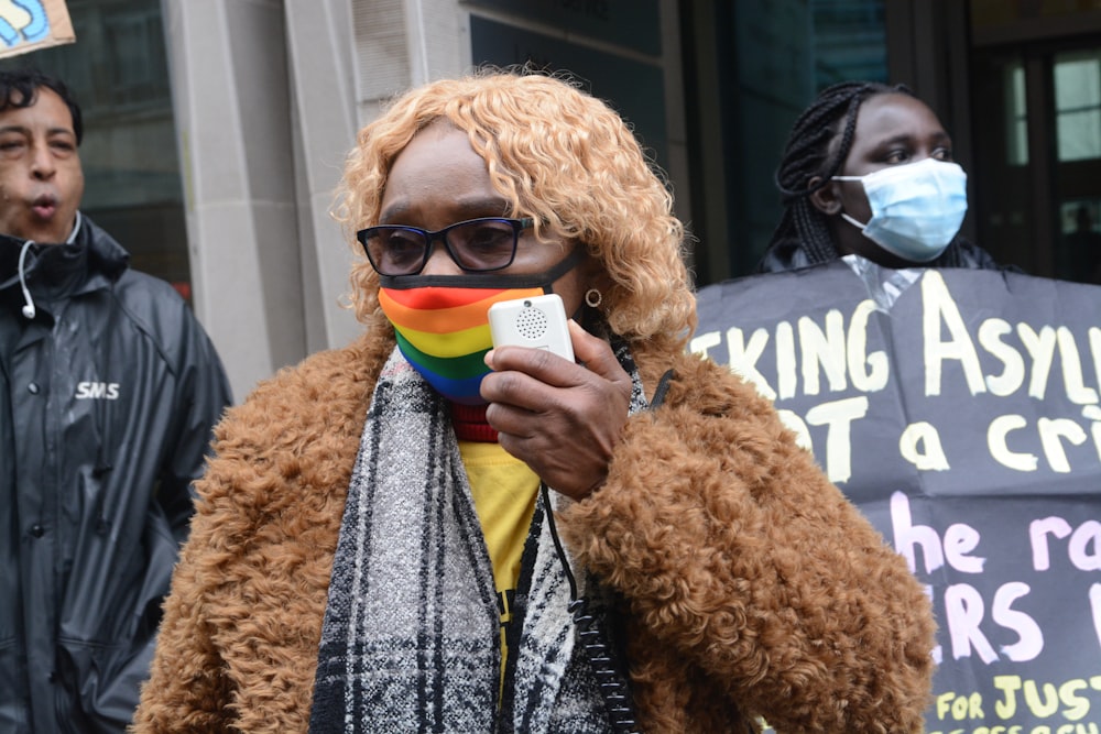 a woman wearing a face mask and holding a rainbow flag