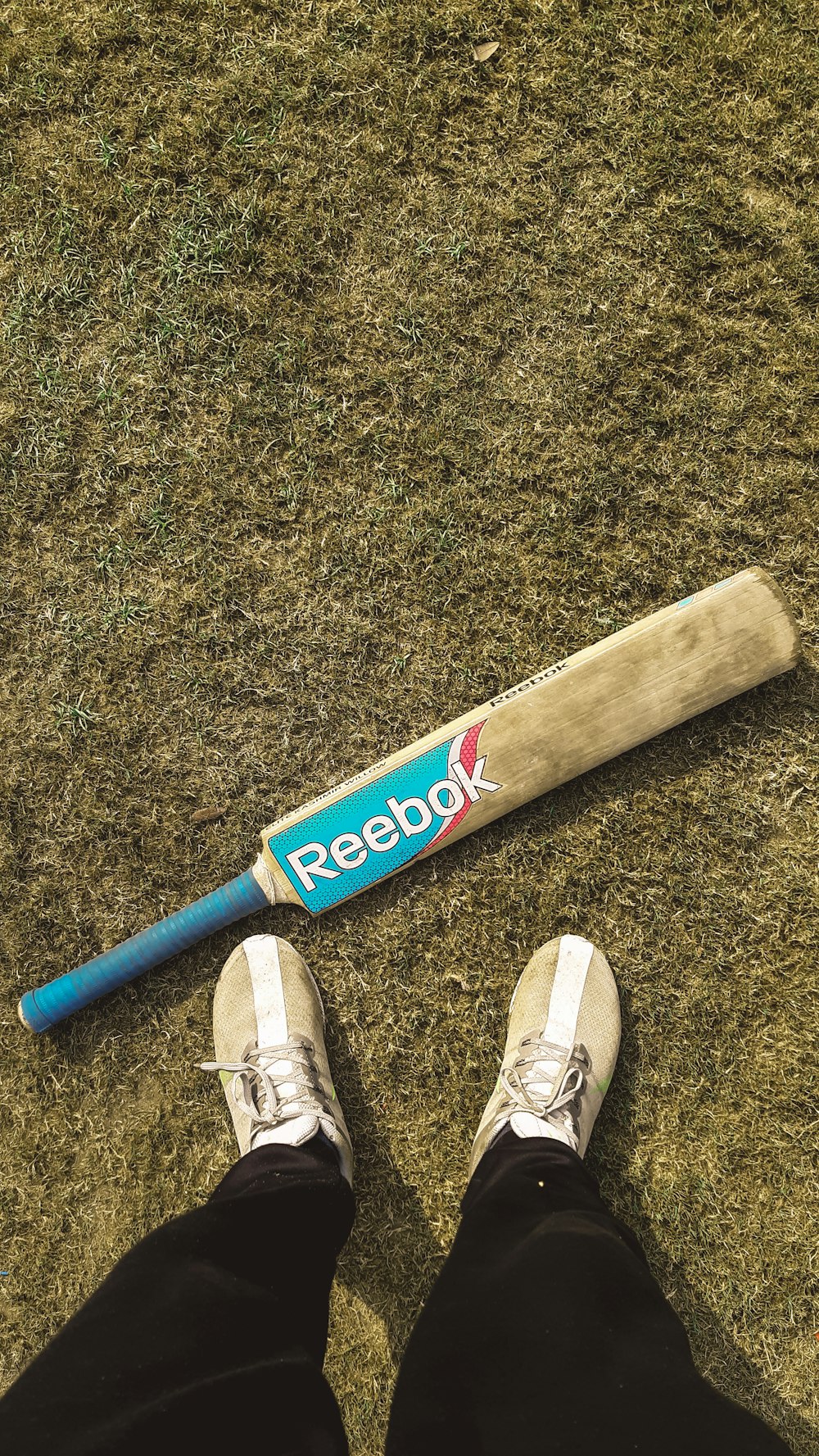 a baseball bat laying on the ground next to a person's feet