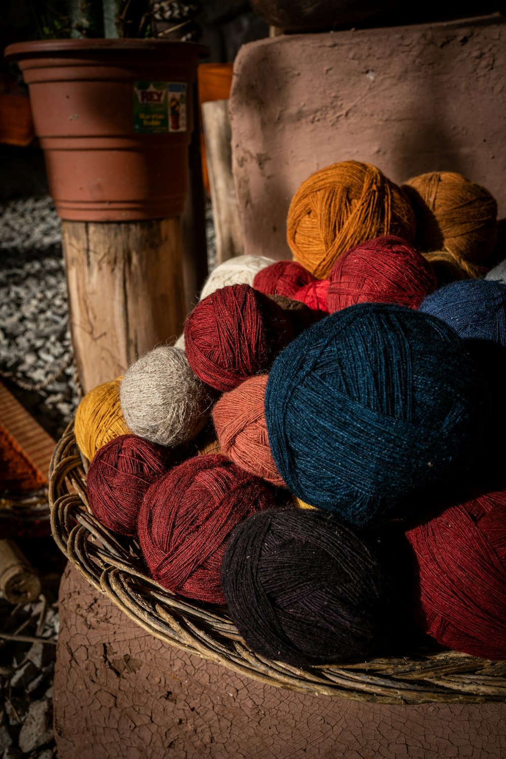 a basket filled with balls of yarn next to a potted plant