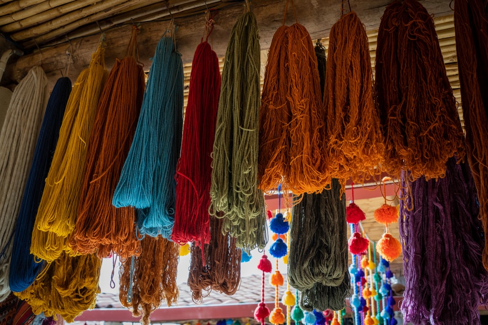 a bunch of different colors of yarn hanging from a ceiling