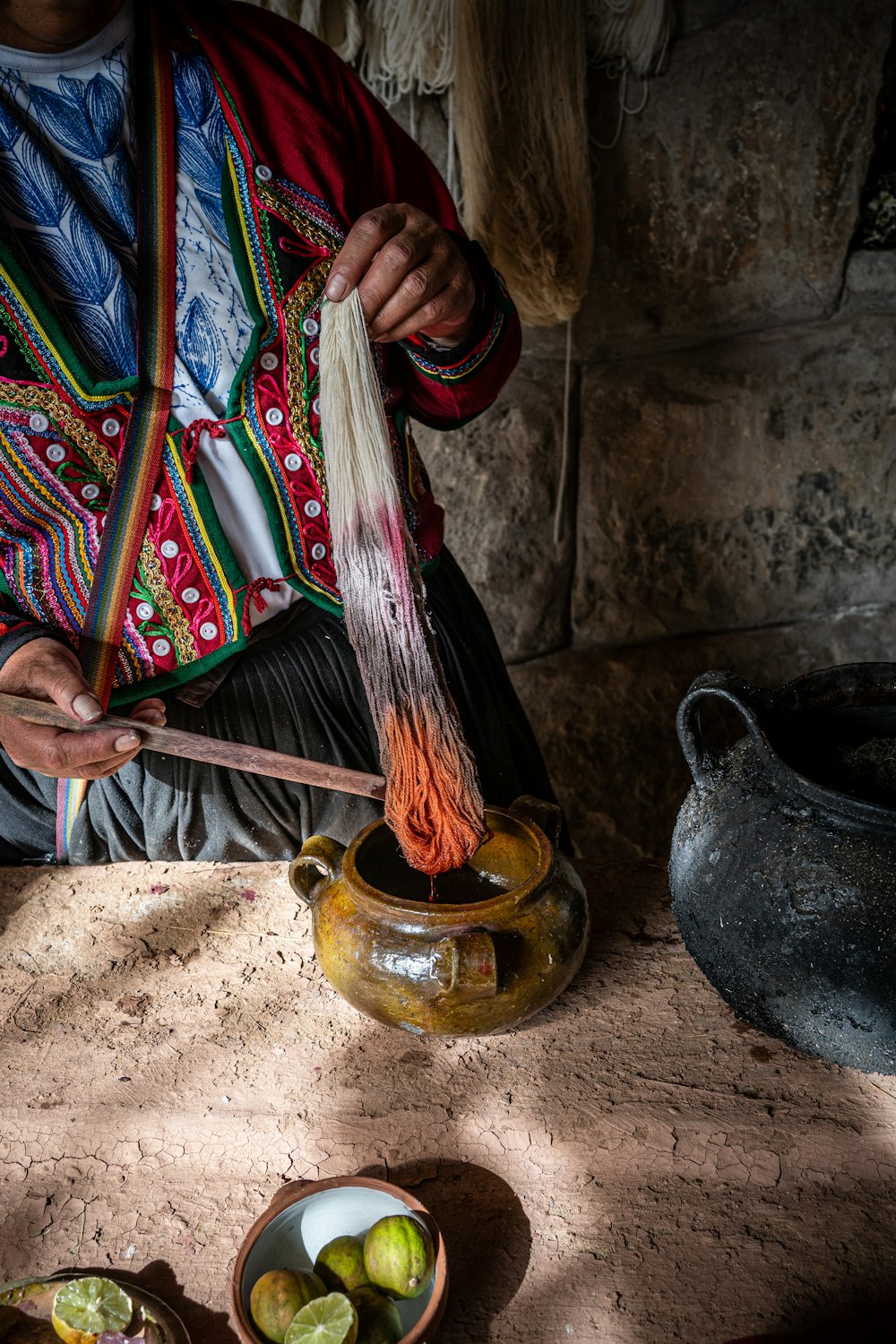 a woman in a colorful jacket is stirring a bowl of fruit