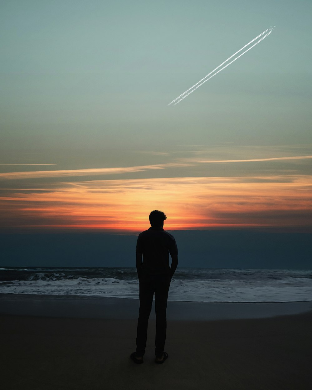 a man standing on top of a beach next to the ocean