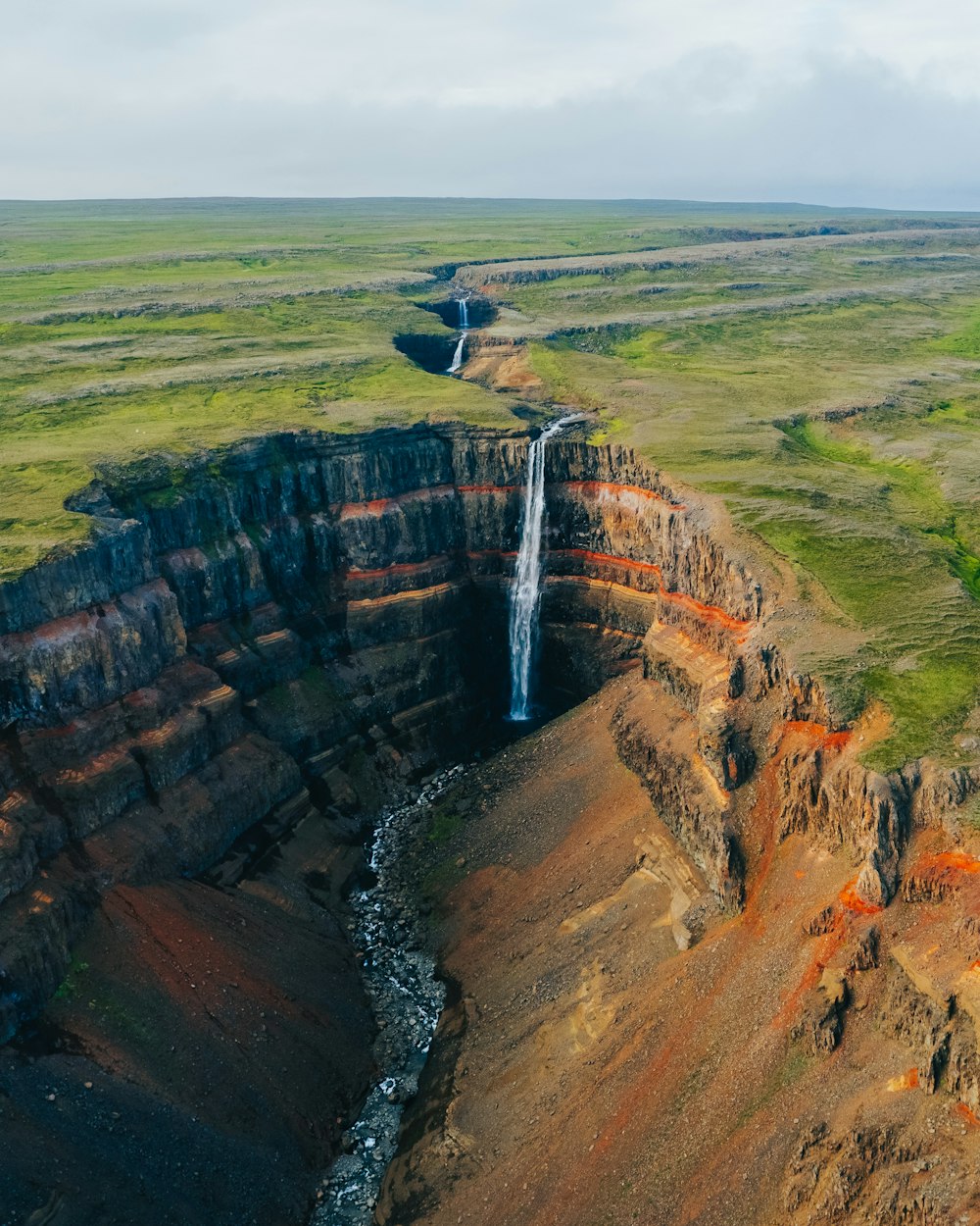 an aerial view of a waterfall in a canyon