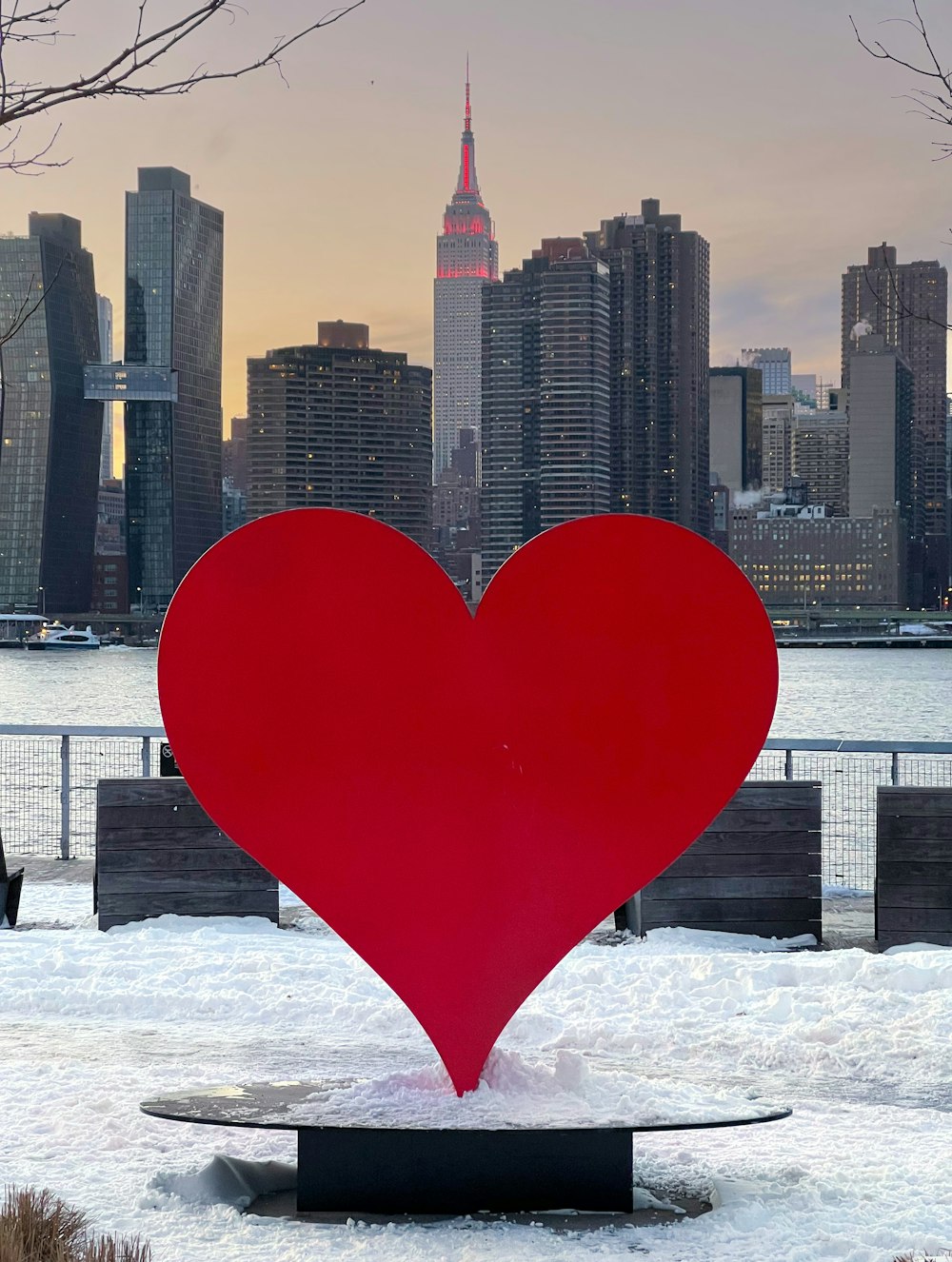 Eine große Skulptur mit rotem Herzen vor der Skyline der Stadt