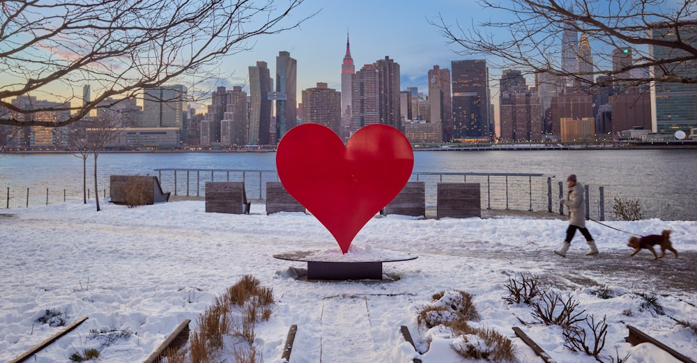 a person walking a dog in front of a large heart sculpture