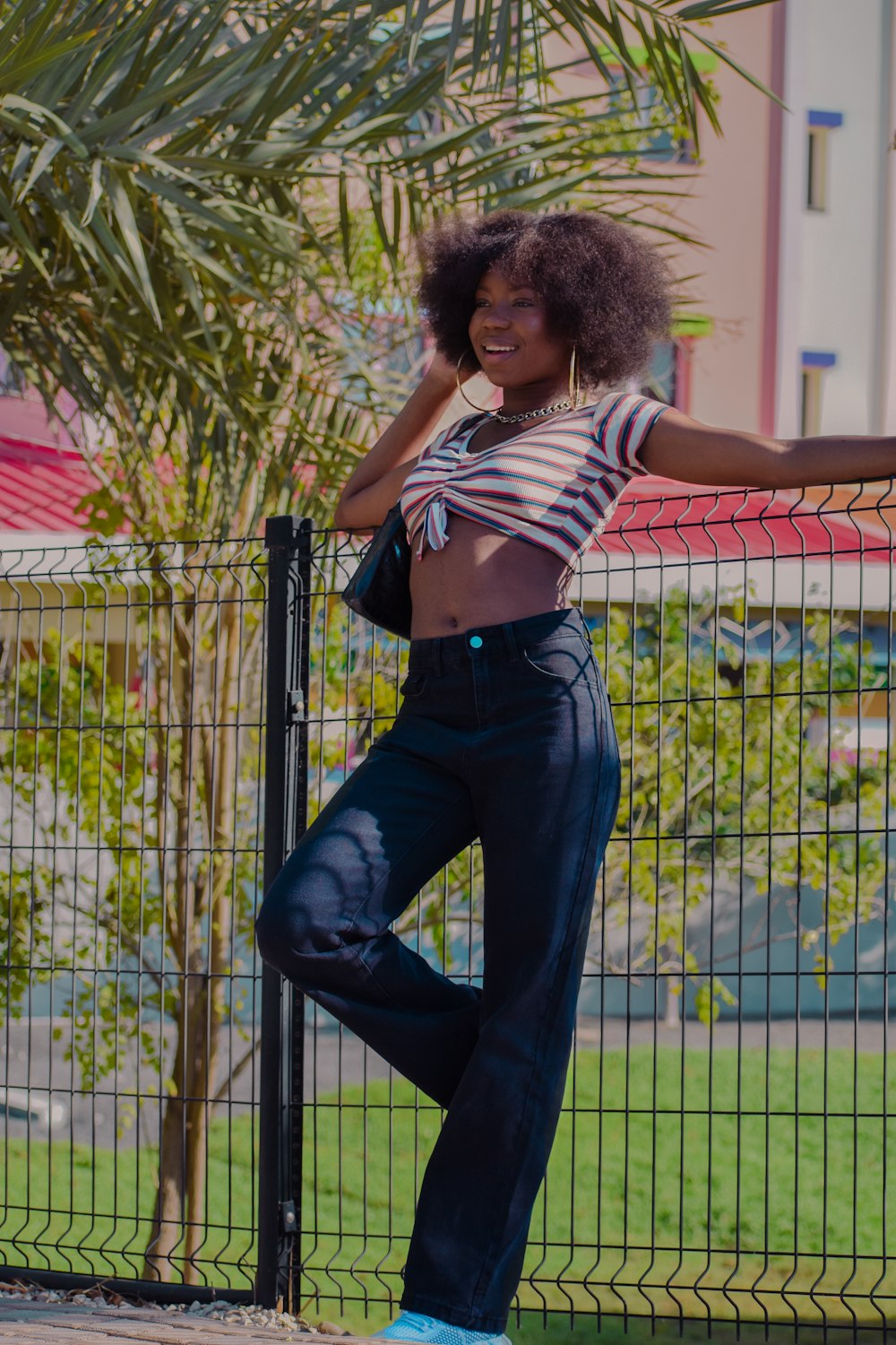 a woman leaning against a fence with her hand on her hip