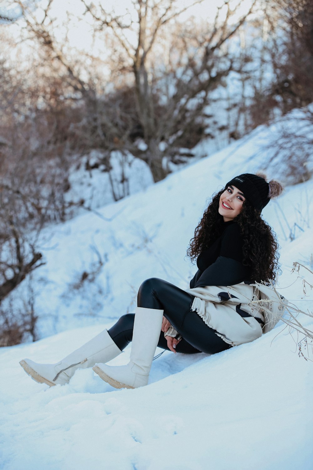 a woman sitting in the snow wearing boots