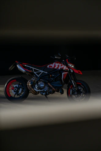 A sleek display of various motorcycle lubricant bottles arranged by viscosity and type, with a blurred background of a red sports motorcycle.