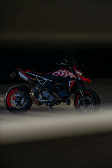 Close-up of a sleek black motorcycle with red accents under moody lighting