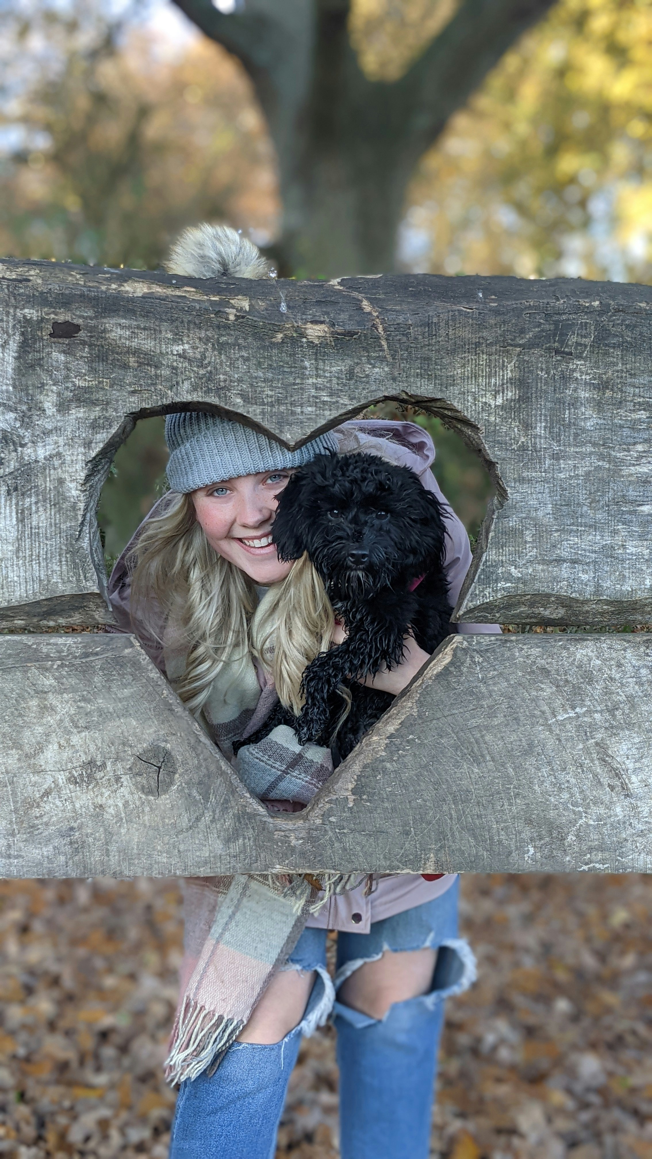 a woman holding a black dog in a heart shaped hole