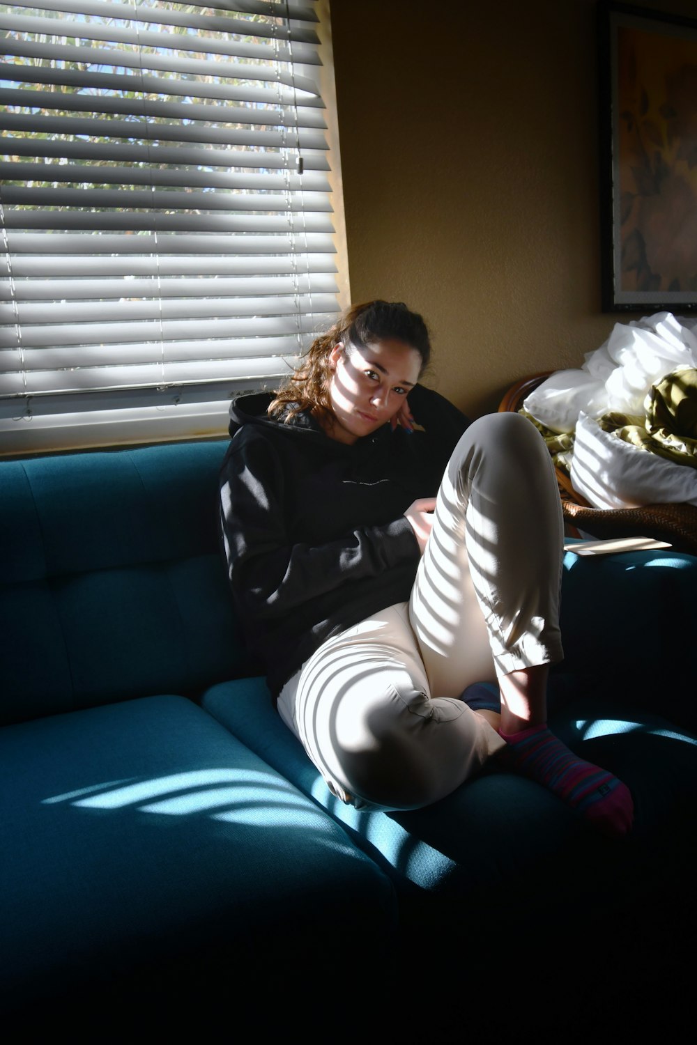 a woman sitting on a blue couch in front of a window