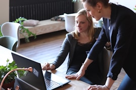 two women looking at a laptop on a table