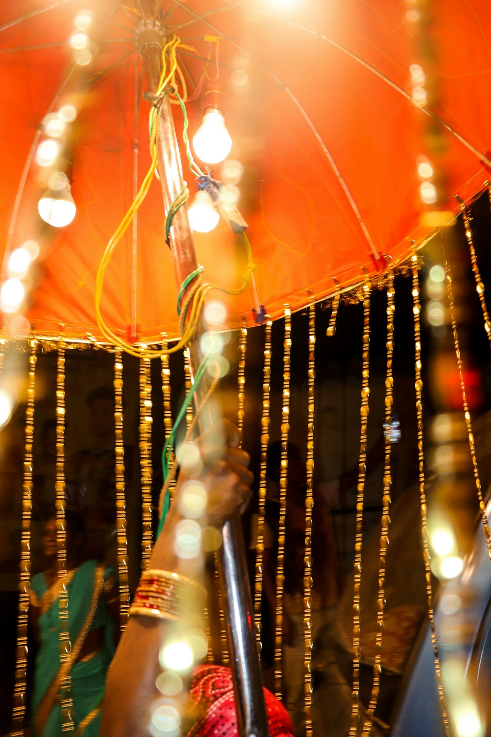 a person holding an umbrella in front of a string of lights