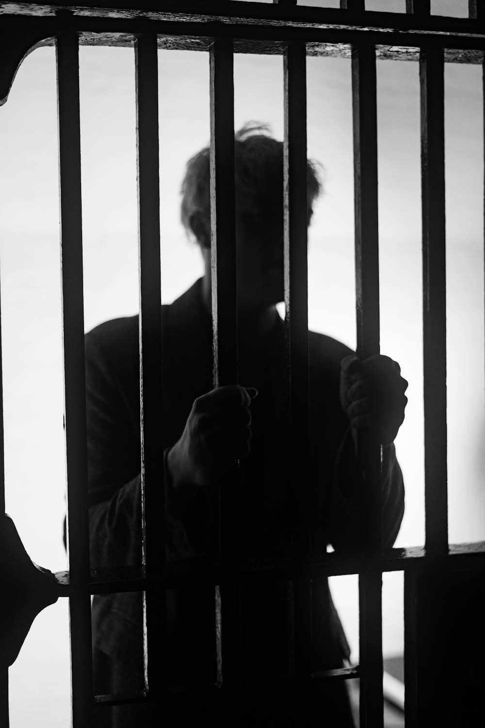 a man standing behind bars in a jail cell