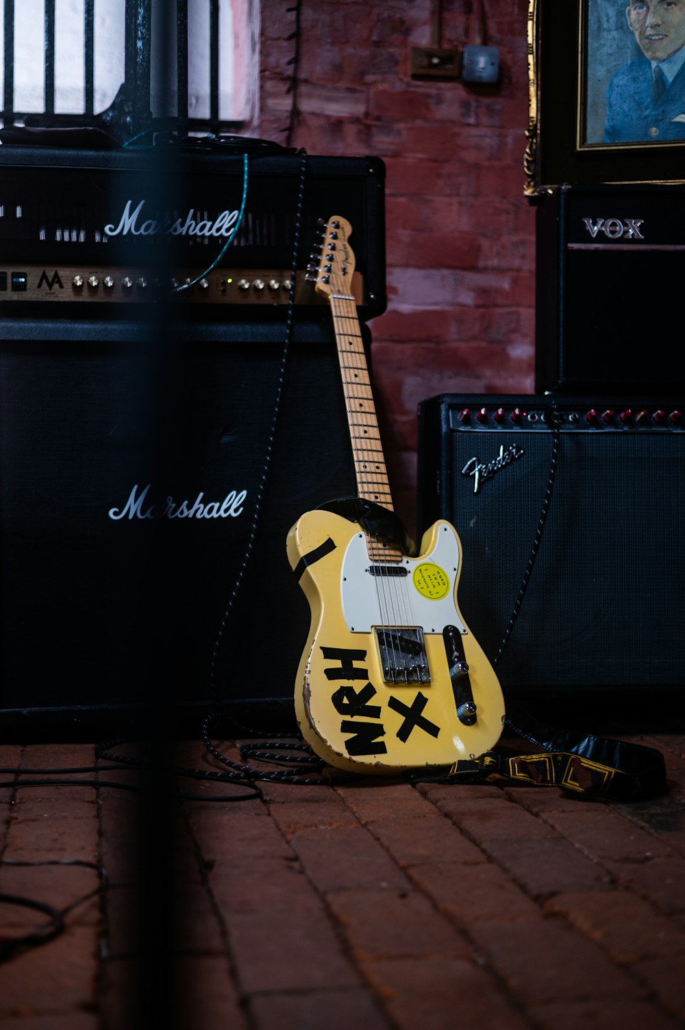 a yellow guitar sitting on a brick floor