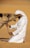a man in a white outfit is petting a camel