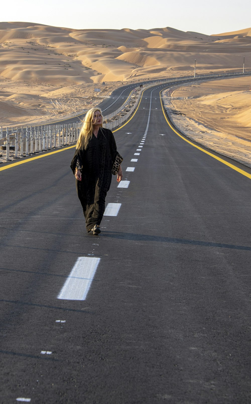 a woman walking down the middle of a road