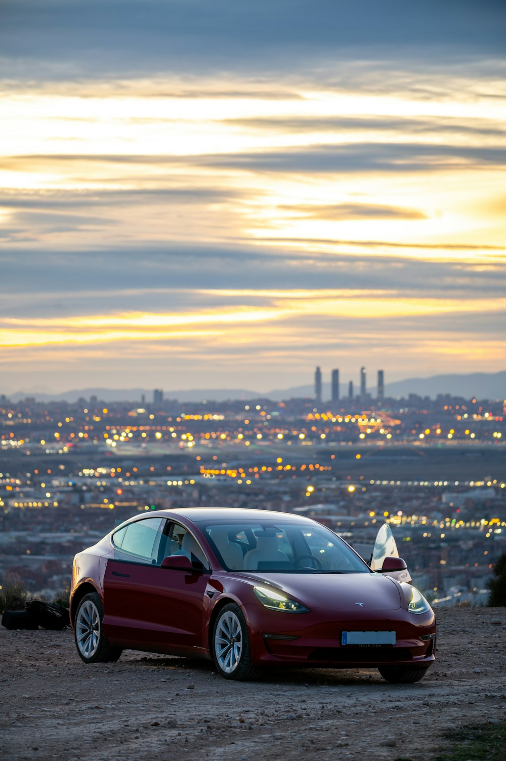 a red car parked on top of a dirt field