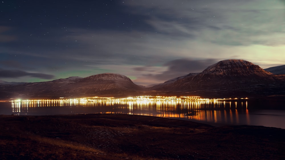 a night scene of a lake with mountains in the background
