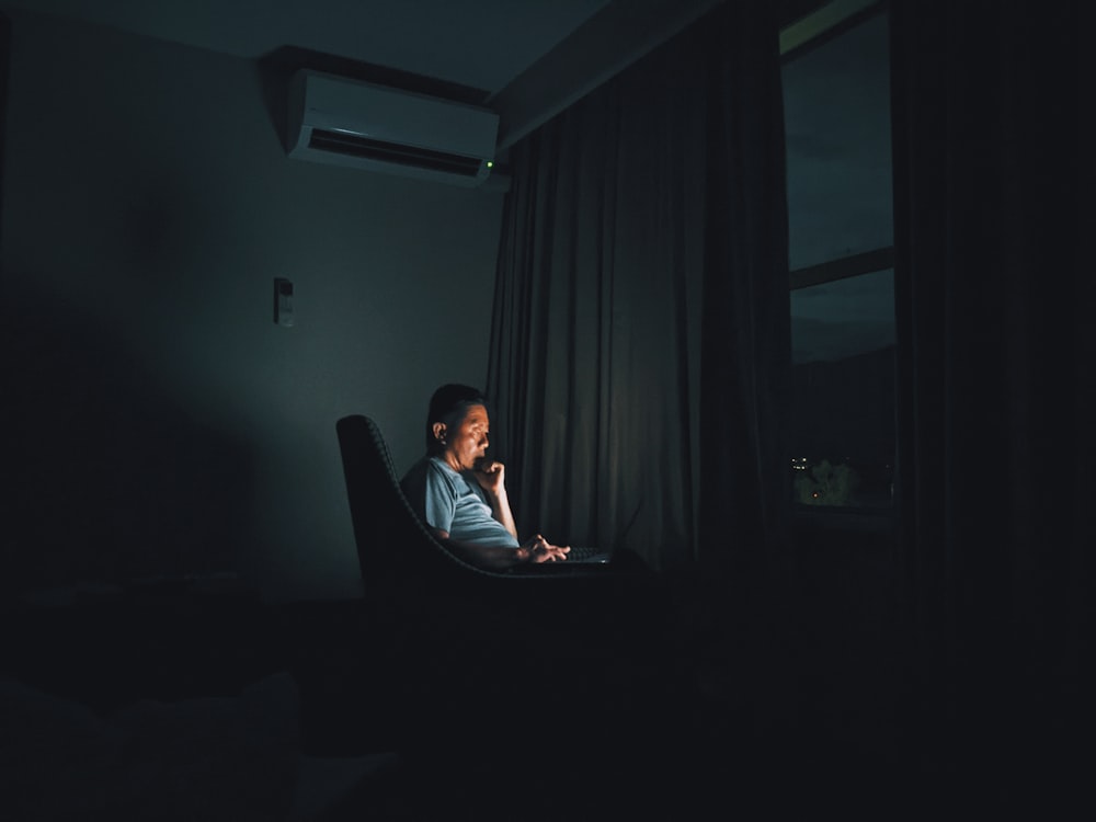 a woman sitting in a chair in a dark room