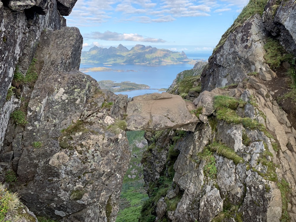 a rocky cliff with a view of a body of water