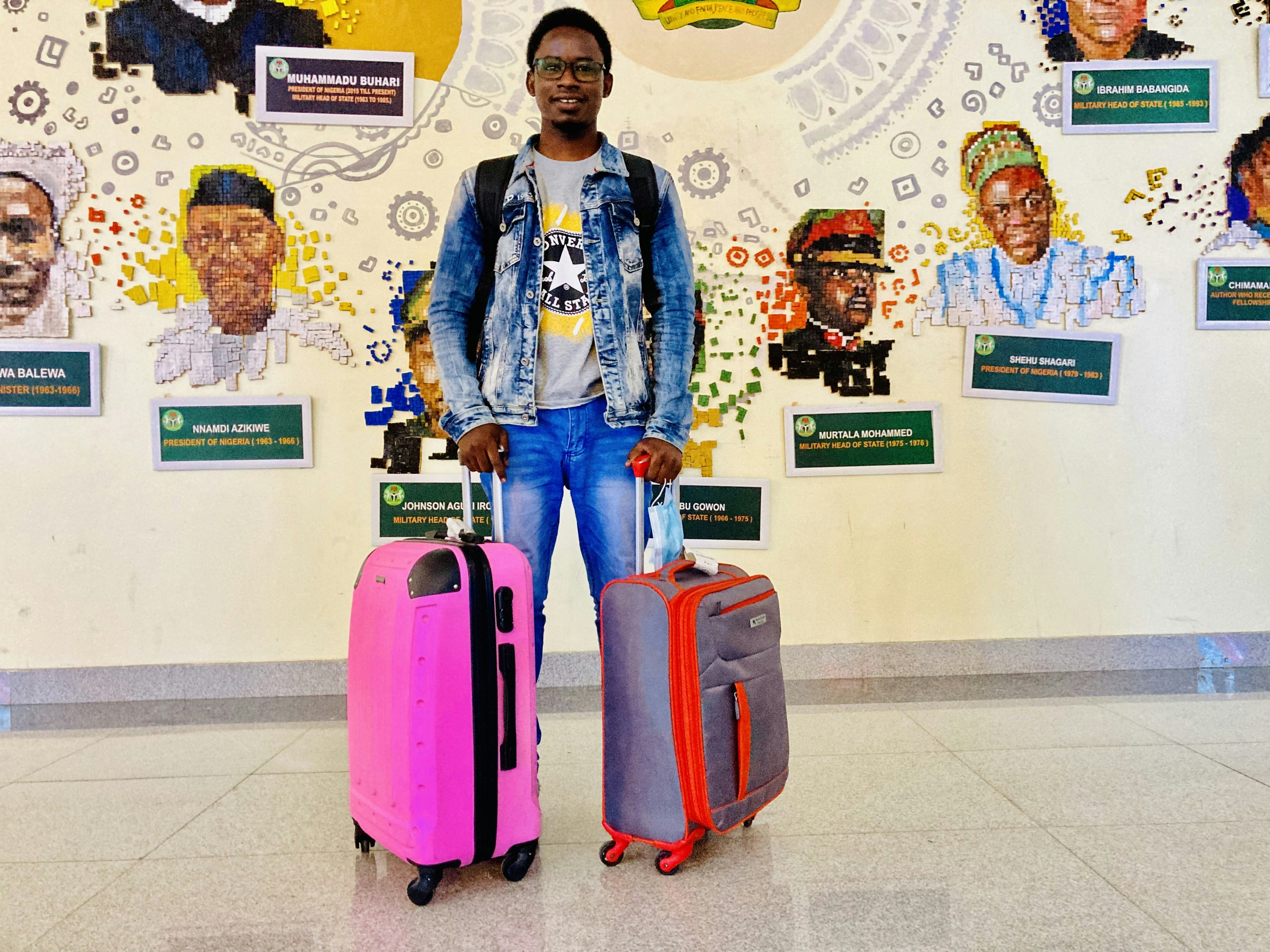 a man standing with two suitcases in front of a wall