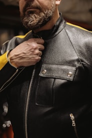 a man in a leather jacket adjusts his tie