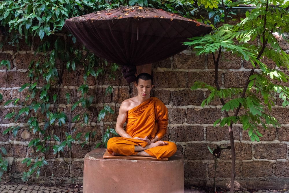 a man sitting in a meditation position under an umbrella