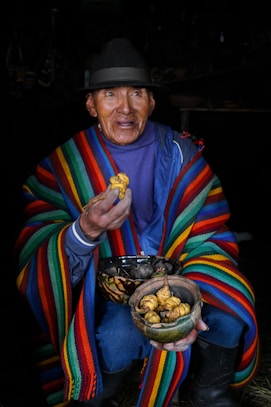 a man in a colorful blanket holding a bowl of food