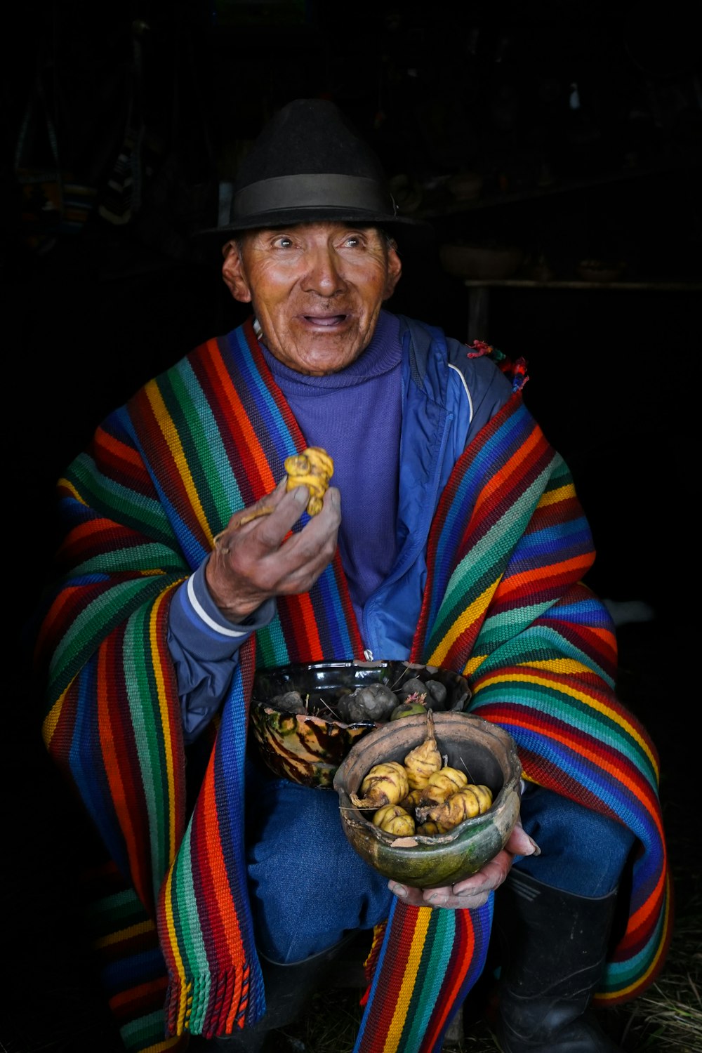 a man in a colorful blanket holding a bowl of food