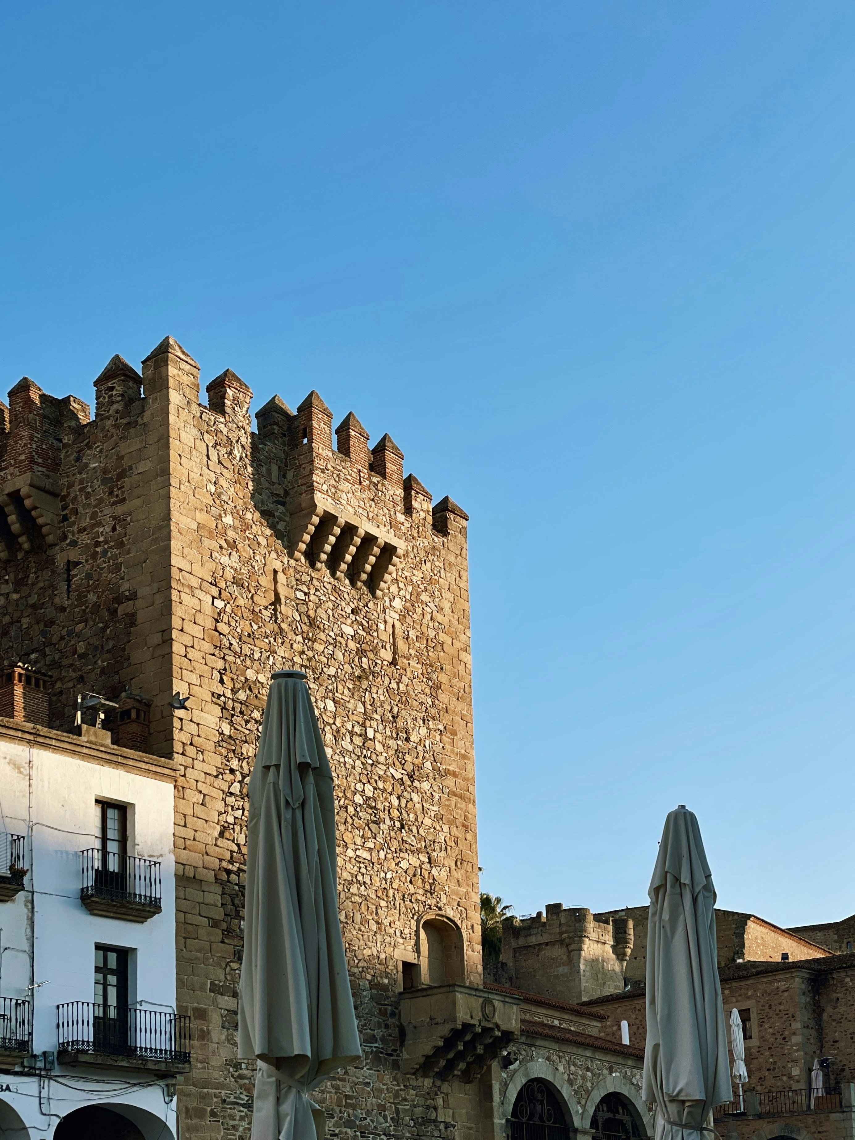 Un castillo como edificio con mesas y sombrillas frente a él