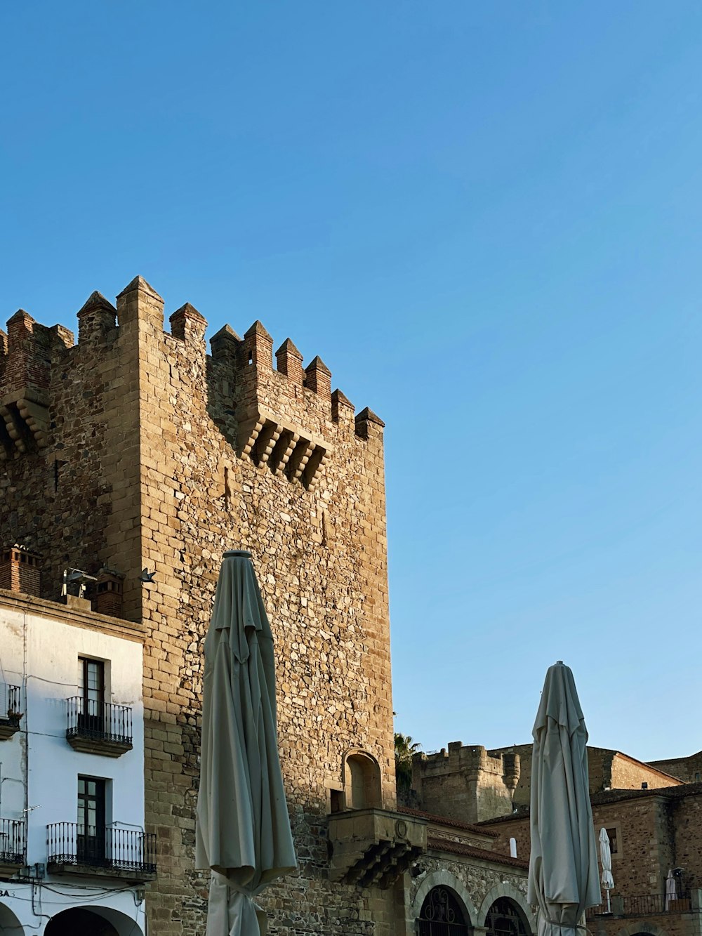 Un castillo como edificio con mesas y sombrillas frente a él