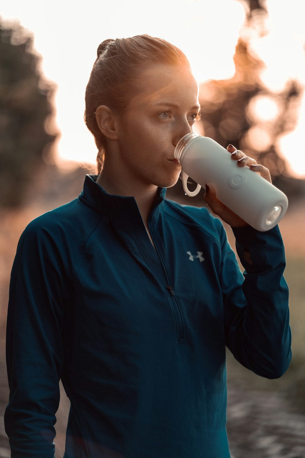 a woman drinking from a white cup