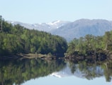 A serene lake reflecting snow-capped mountains under a clear blue sky.